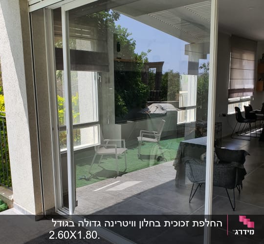 דלת זכוכית גדולה עם מסגרת לבנה במרפסת